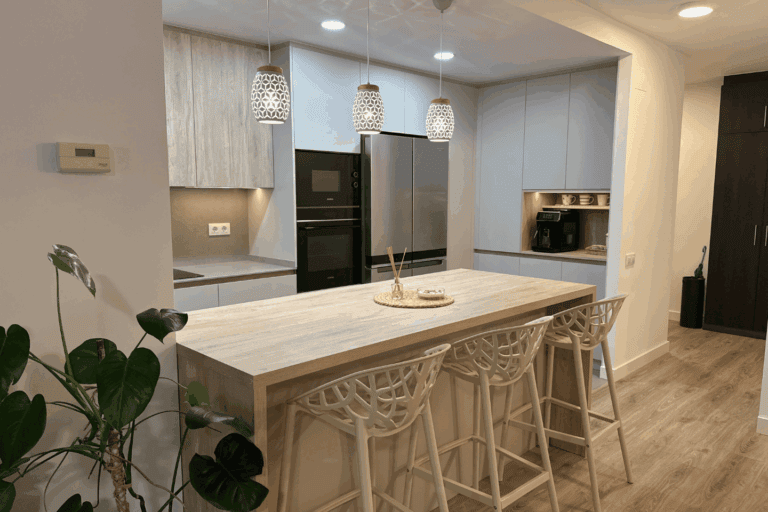 Cocina abierta al salón con isla central y mobiliario fabricado a medida.